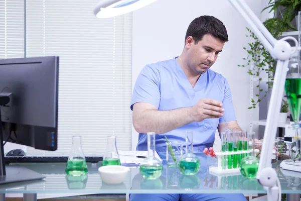 Junger kaukasischer Wissenschaftler, der eine Lösungsprobe aus einem Reagenzglas nimmt — Stockfoto