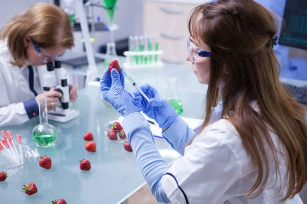 Widok z powrotem kobiet naukowiec samodzielnym chemikaliów w strawberrie — Zdjęcie stockowe