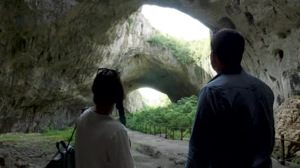 Ζευγάρι κοιτάζοντας μια μεγάλη σπηλιά στα βουνά — Αρχείο Βίντεο