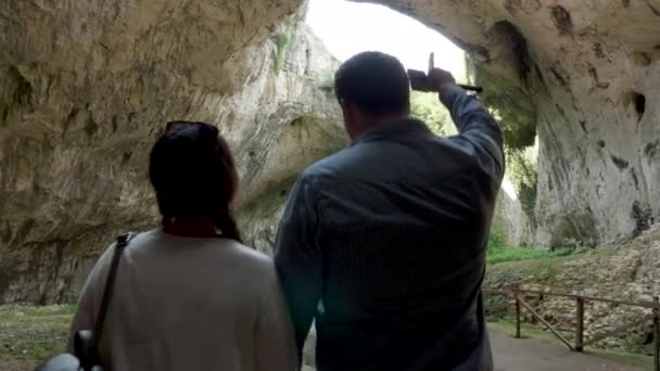 Paar wandelen en het verkennen van een grote grot in de bergen — Stockvideo