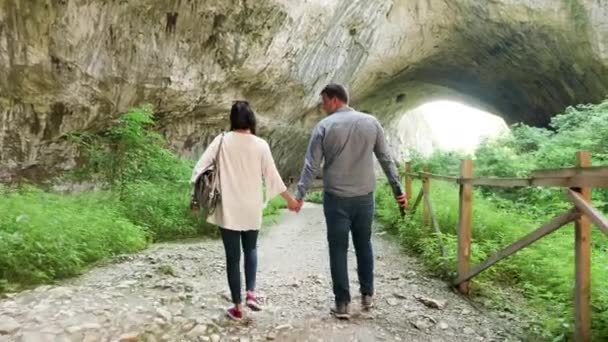 Casal de turistas andando em uma grande caverna — Vídeo de Stock