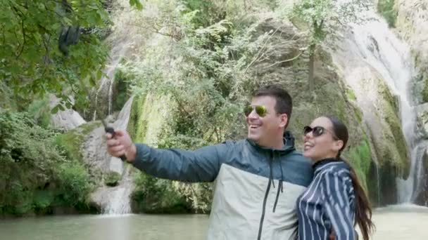 Bliska strzał para biorąc selfie w pobliżu wodospadu — Wideo stockowe