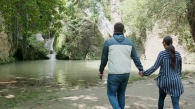 Turist çift bir şelale yakın yürüyor ve ona bakıyor