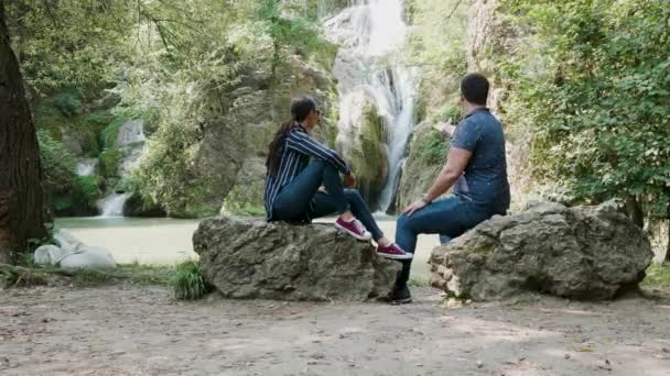 Junges schönes Paar bewundert einen Wasserfall — Stockvideo