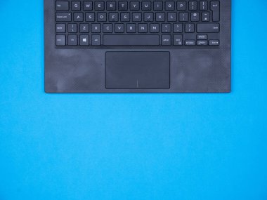 Düz mavi arka plan üzerinde modern laptop üst görünümü yatıyordu