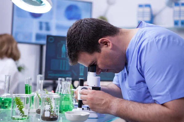 Homem cientista olhando através do microscópio depois de vírus em um laboratório de pesquisa para a indústria agrícola — Fotografia de Stock