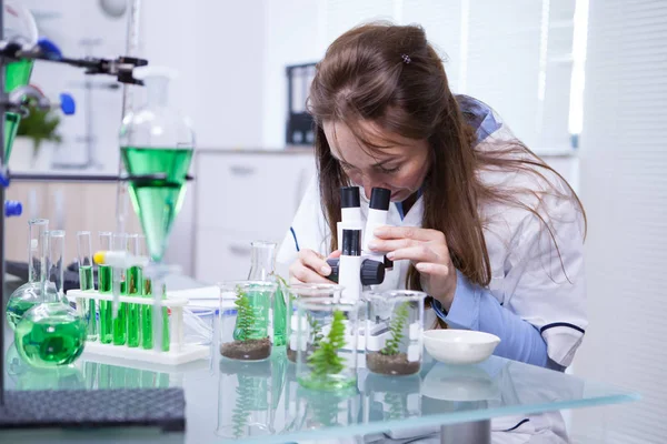 Femme scientifique ajustant son microscope dans un laboratoire de biotechnologie — Photo