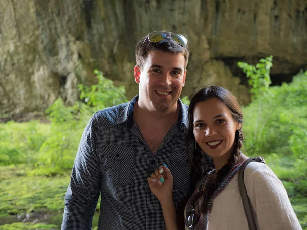 Beautiful young couple smiling to the camera in a mountain cave — Stock Photo, Image