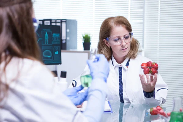 Caucasian female scientist looking at strawberries in her research lab — Stock Photo, Image