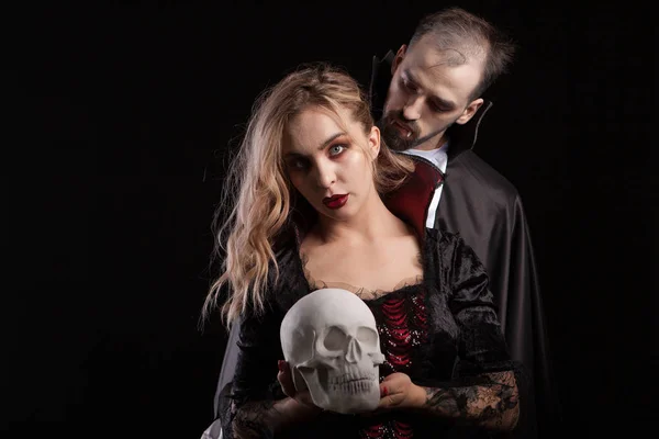 Porträt eines als Dracula verkleideten jungen Mannes, der auf den Hals seiner Vampirfrau blickt — Stockfoto