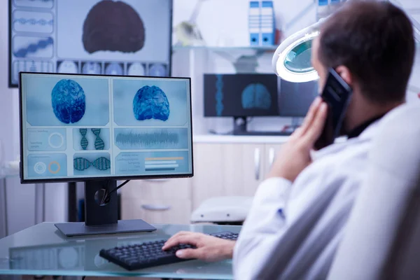 Medico maschile utilizzando il telefono mentre si lavora sulla digitazione del computer — Foto Stock