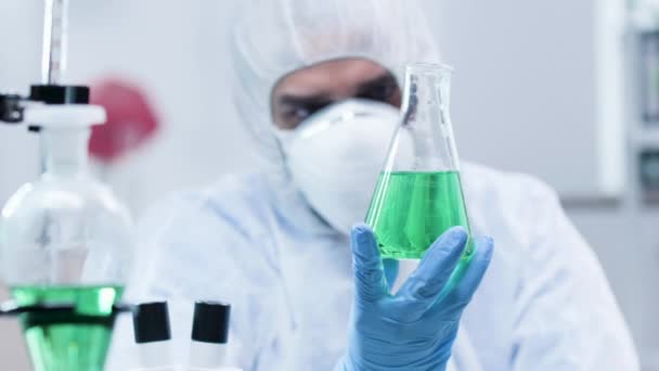 Biotecnólogo olhando para uma amostra com líquido verde — Vídeo de Stock