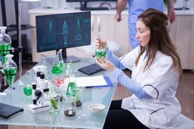 Bir araştırma laboratuvarında yeşil bir çözüm ile çalışan olgun bilim adamı