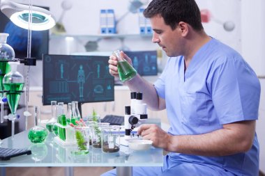 Araştırma laboratuvarında yeşil bir çözüm tutan genç bilim adamının yan görünümü