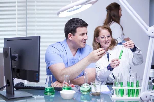 Team van gevorderde wetenschapper die de oplossing controleert vanuit een reageerbuis in hun laboratorium — Stockfoto