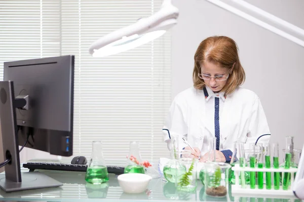 Сосредоточенная женщина среднего возраста делает заметки после научных испытаний в производственной лаборатории — стоковое фото