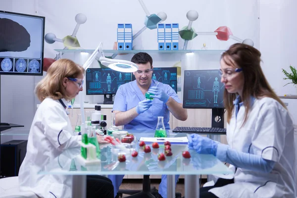 Joven científico caucásico con dos científicas trabajando en una investigación de laboratorio — Foto de Stock