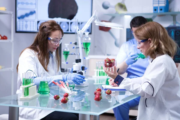 Científica caucásica sosteniendo una caja de fresas después de hacer pruebas biológicas — Foto de Stock