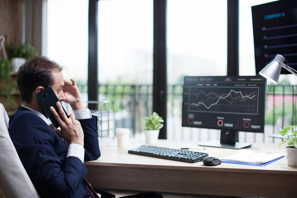 Boční pohled na mladého obchodního muže, jak mluví po telefonu a přemýšlí o své marketingové strategii — Stock fotografie