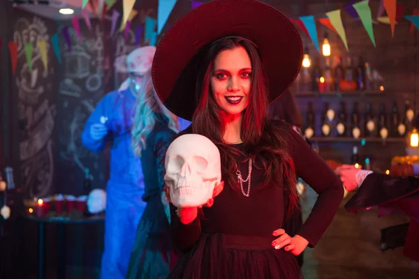 Mulher bonita vestida como um com para halloween com um chapéu mágico na cabeça — Fotografia de Stock