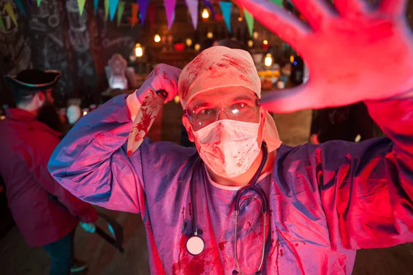 Expression faciale d'un homme effrayant habillé comme un médecin tenant un couteau à la fête d'Halloween — Photo