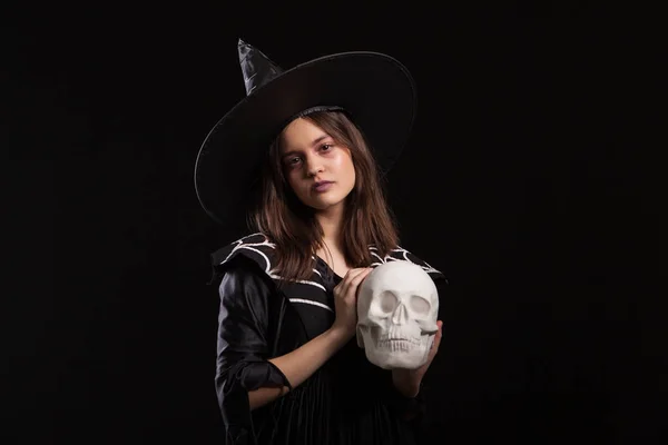 Портрет маленькой девочки, дозирующей темное колдовство человеческим черепом на Хэллоуинском карнавале — стоковое фото