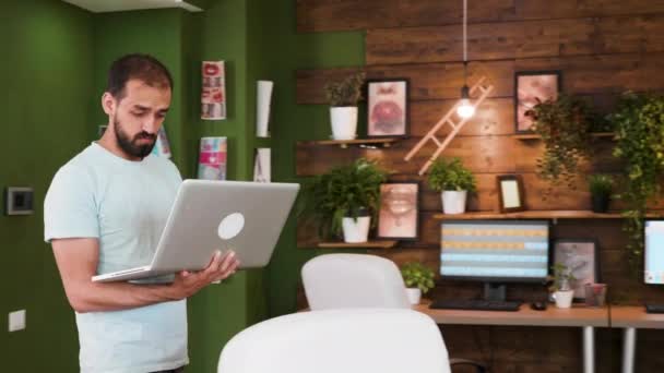 Diretor de arte criativo entrando no escritório segurando seu laptop e olhando para o conselho de design — Vídeo de Stock