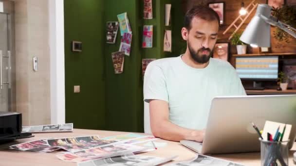 Δημιουργικός επιχειρηματίας δακτυλογραφεί στο laptop του, ενώ κάθεται στο γραφείο του — Αρχείο Βίντεο