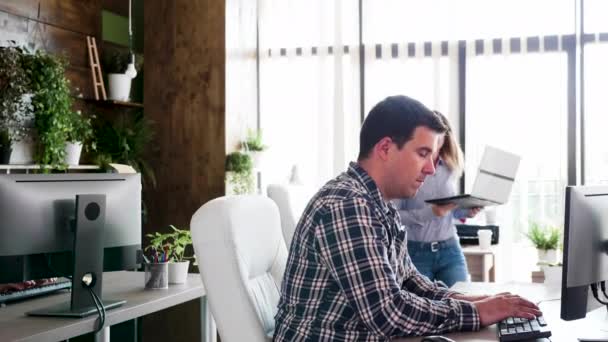 Jovem empresário dedicado trabalhando em seu computador enquanto seus gerentes vêm para sua mesa — Vídeo de Stock