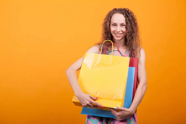 Glad ung dam leende med shoppingväskor i hennes händer — Stockfoto