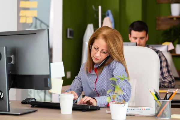 Woman talking on the phone and typing — Stock Photo, Image