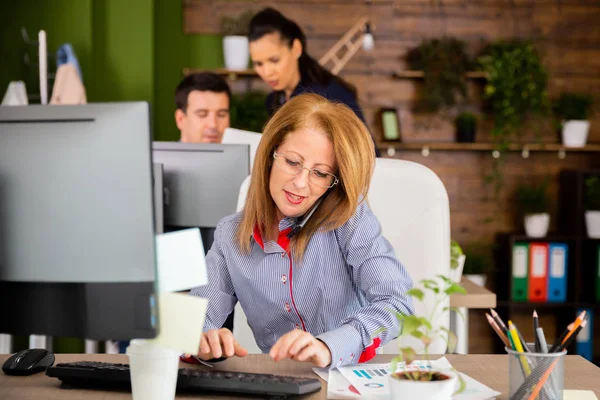 Mujer del medio escribiendo mientras tiene una conversación seria en su teléfono — Foto de Stock