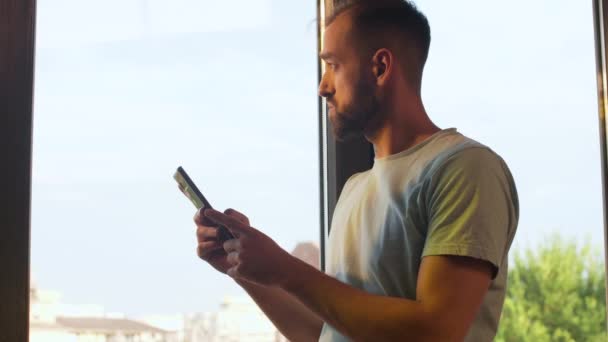 Менеджер стартапа Unicorn смотрит на свой телефон у большого окна в офисе — стоковое видео