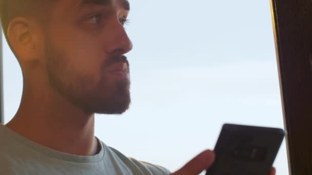 Man looking at his phone near a big window in the office — Stock Video