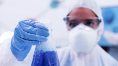 Sigara mavi sıvı ile bir şişe tutan koruma ekipmanları kadın bilim adamı yakın