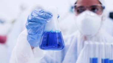 Bir laboratuvarda kadın bilim adamı bir şişe de sigara mavi sıvı alarak ve tutarak