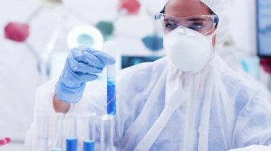 Sigara mavi solüsyonu ile bir test tüpü tutan tulum tüm ekipman kadın araştırmacı