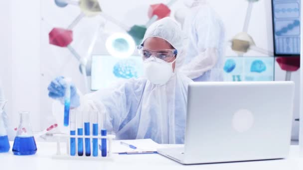Ciências femininas segurando um tubo de teste com líquido azul fumante e fórmula de escrita — Vídeo de Stock
