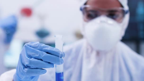 Крупным планом химик-исследователь держит пробирку с курением голубой фуид — стоковое видео
