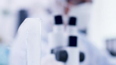 Kimyager bilim adamının bir şişe sigara içen mavi sıvı alarak elini yakın