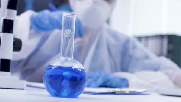 Φορητό υλικό από επιστήμονα που προσθέτει αντιδραστήριο σε ένα μπλε υγρό — Αρχείο Βίντεο