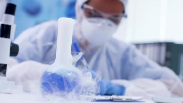 Imágenes de mano de líquido azul con reactivo fumando en un laboratorio de química — Vídeos de Stock