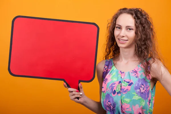 Lachende vrouw houdt een lege banner in Studio over oranje achtergrond — Stockfoto