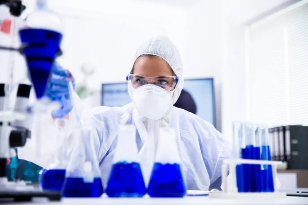 Cientista feminina em equipamento de macacão olhando para uma amostra — Fotografia de Stock