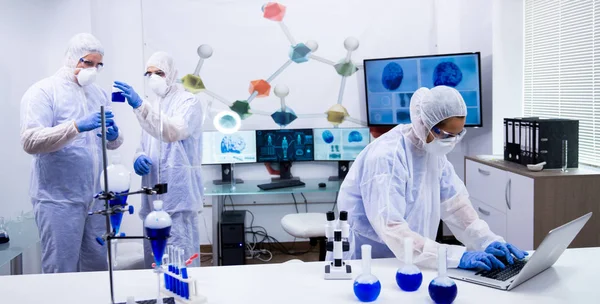 Equipo de científicos en equipos de protección que trabajan en un moderno laboratorio de investigación — Foto de Stock