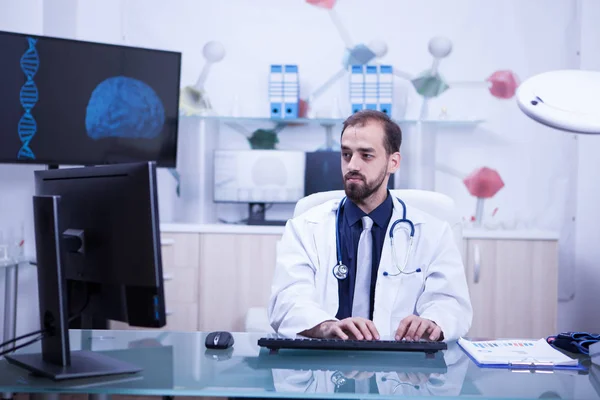 Joven médico guapo trabajando y escribiendo en su gabinete —  Fotos de Stock