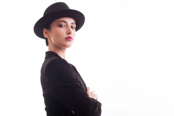 Confident fashion model with stylish black hat looking at the camera over white background in studio Stock Image