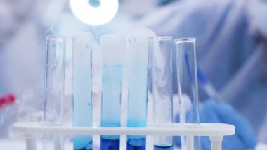 Test tüplerinde sigara mavi sıvı üzerinde pipet ile çözüm ekleyerek bilim adamı yakın