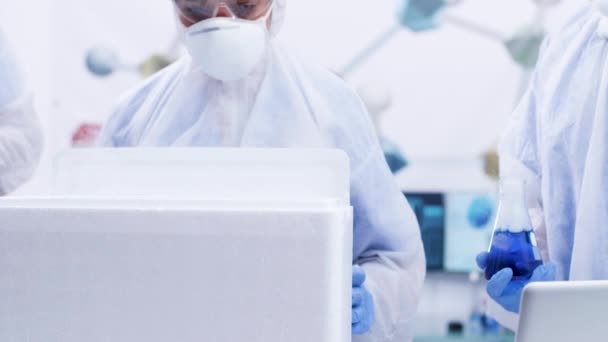 Φορητά πλάνα από έκπληκτη γυναίκα επιστήμονα ανοίγοντας ένα κουτί χημικών ψυγείο στο σύγχρονο εργαστήριο — Αρχείο Βίντεο