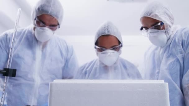 Ομάδα επιστημόνων που κοιτάζει προσεκτικά σε ένα κουτί ψυγείου και βγάζει έναν ιό καπνίσματος σε επαφή με τον αέρα — Αρχείο Βίντεο